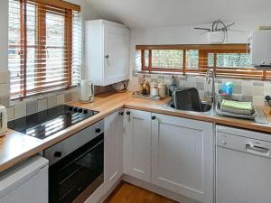 a kitchen with white cabinets and a sink at Hay Loft -23894 in Aylmerton