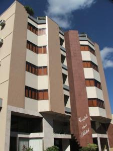 ein hohes weißes Gebäude mit braunen Fenstern in der Unterkunft Crystal Apart Hotel in Macaé