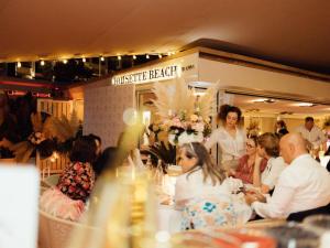 a group of people sitting around a table in a restaurant at Croisette Beach Hotel Cannes - MGallery Collection in Cannes