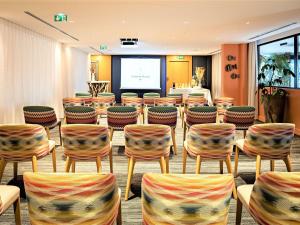 a conference room with chairs and a projection screen at Croisette Beach Hotel Cannes - MGallery Collection in Cannes