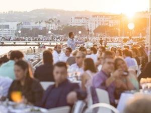 a large group of people sitting at a party on the beach at Croisette Beach Hotel Cannes - MGallery Collection in Cannes