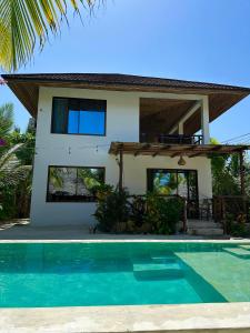 a villa with a swimming pool in front of a house at Sand Beach Boutique Apartments in Bwejuu