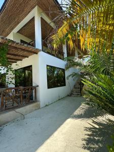 a white building with a porch and some palm trees at Sand Beach Boutique Apartments in Bwejuu