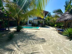 a resort with a swimming pool and palm trees at Sand Beach Boutique Apartments in Bwejuu +9 photos