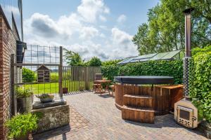 a patio with a hot tub and a grill at Gastsuite het Duinroosje met hottub op het privé terras! in Den Burg +9 photos