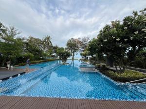 a large swimming pool with blue water and trees at Relaxing Link to beach with pool in Hua Hin