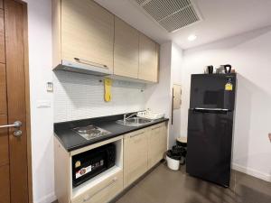a kitchen with a black refrigerator and a sink at Relaxing Link to beach with pool in Hua Hin
