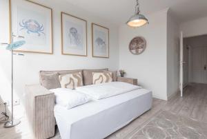 a white bed in a room with drawings on the wall at Haus Heidehörn, App 7 in Wenningstedt
