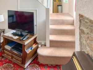 a living room with a flat screen tv and stairs at Kiln Cottage in Bolton le Sands