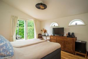 a bedroom with a bed and a flat screen tv at Gastsuite het Duinroosje met hottub op het privé terras! in Den Burg