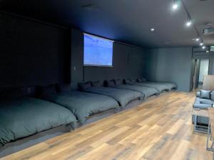 a row of beds in a room with a tv at Black Penthouse Naha 最大12名宿泊可 118平米 国際通り沿い 牧志駅 徒歩5分 in Naha