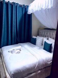 a large bed with blue curtains on it at Kapere cozy room in Kisumu