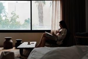 a woman sitting in a chair with a laptop at Hotel Anilevich Mansion in Beer Sheva