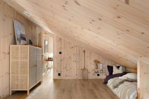 an attic bedroom with wooden walls and a bed at Cabin Overlooking Ryfylke Fjord in Høyvik