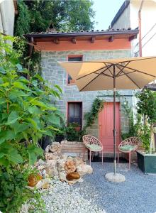 a patio with an umbrella and chairs and a building at C'ERA UNA VOLTA... in Mornico Losana