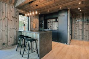 a kitchen with black cabinets and bar stools at Modern Mountain Cabin Near Syningtoppen in Torpo +26 photos