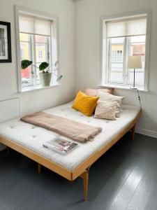 a bed sitting in a room with two windows at Live In Classic Skagen House In Skagen's Heart in Skagen