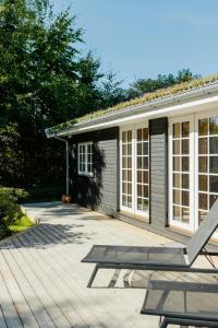una casa con terraza y una silla delante de ella en Bjælkehus Tæt På Havet Og Charmerende Kystbyer, en Græsted