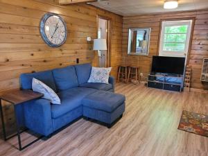 un soggiorno con divano blu e orologio sul muro di Castaways Cottage on Croton Pond #2 a Newaygo Altre 9 foto