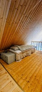 a bed in a room with a wooden wall at Cottage By The Stream In Southern Halland in Laholm