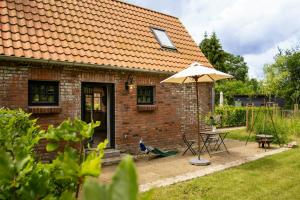 a brick house with a table and an umbrella at Oasis Of Peace Near The Lake in Langen Jarchow