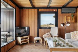 洛肯70'S Style Summerhouse Near Løkken的带电视和桌子的客厅