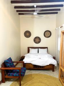 a bedroom with a bed and a chair at Tulivu Zanzibar in Bwejuu