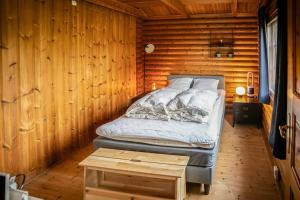 a bedroom with a bed in a wooden cabin at Finnish-Inspired Log Cabin Near Beach in Slagelse