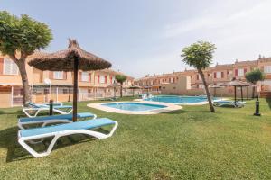 einen Pool mit Liegestühlen und einem Sonnenschirm in der Unterkunft Puerta Marina Costa de la Luz in La Redondela