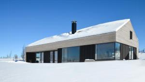 a building with glass windows in the snow at Cabin Overlooking Hallingskarvet National Park in Geilo