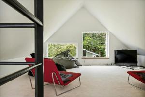 un salon avec une chaise rouge et une télévision dans l'établissement Fjord-Close Cottage With Beautiful View, à Hemmet
