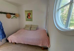 a small bed in a room with a window at Cottage In Woodland Garden In Natural Harmony in Asnæs