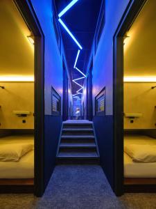 a hallway with two beds and a blue light at The Hyve Capsule Amsterdam in Amsterdam