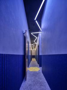 a hallway with blue walls and a hallway with lights at The Hyve Capsule Amsterdam in Amsterdam