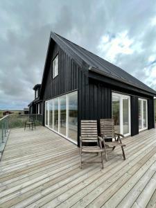 a black house with two chairs on a wooden deck at Luxury With Pool In Dunes Near Løkken in Løkken