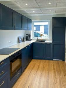 una cucina con armadi blu e pavimenti in legno di Beach House In Tørresø For Family Gatherings a Otterup Altre 13 foto
