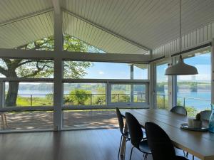 a dining room with a table and chairs and a large window at Cottage By Kolding Fjord With Panoramic View in Kolding +7 photos