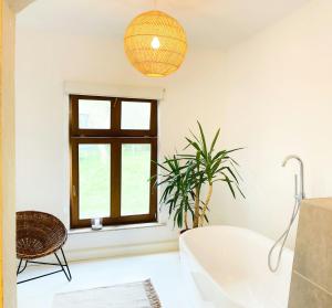 ein Bad mit einer weißen Badewanne und einem Fenster in der Unterkunft Spacious Country House With Idyllic Orchard in Schönwalde