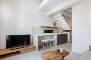 a living room with a flat screen tv and a table at Olive Dryopis Apartments in Kithnos