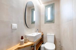a bathroom with a sink and a toilet and a mirror at Olive Dryopis Apartments in Kithnos +12 photos