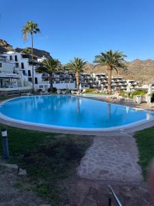a large swimming pool with palm trees and buildings at Toni LuXx Suite Monte Golf in Mogán