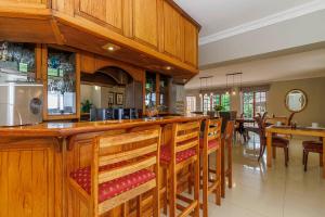 a kitchen with a bar with wooden cabinets and chairs at Churchill House in Hillcrest