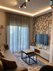 a living room with a tv on a stone wall at Titova Vila - Golden Peak Residence in Zlatibor