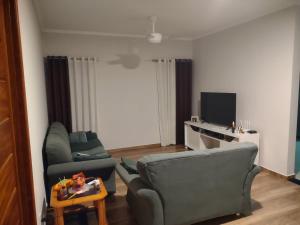 a living room with a couch and a tv at Aconchego Cuesta de Botucatu Ninho verde 2 in Pardinho