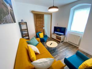 a living room with a yellow couch and a television at Charmante Maison au fil de la Voie Verte in Concarneau