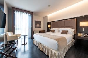 a hotel room with a large bed and a desk at Hotel Diagonal Plaza in Zaragoza