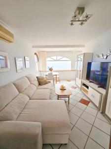 a living room with a white couch and a tv at The lighthouse horizon in Las Lagunas Mijas