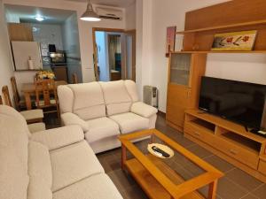 a living room with two white chairs and a flat screen tv at apartamento los montes in Ruidera