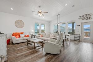 a living room with white furniture and a ceiling fan at Breeze Easy home in Crystal Beach