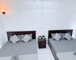 two beds with pillows and a table in a room at NO 10 Kandy by Kepler & Earth in Kandy